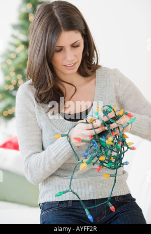 Donna untangling le luci di Natale Foto Stock