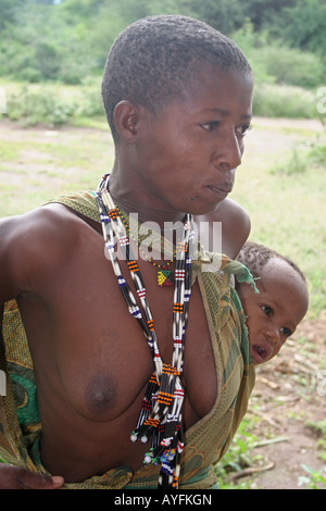 Africa Tanzania Lago Eyasi Ritratto di una giovane Hadzabe madre con il suo bambino legato al suo indietro una piccola tribù di cacciatori-raccoglitori Foto Stock