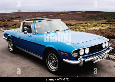 Blue Triumph Stag cabriolet vista in lontananza con North Yorkshire Moors. North Yorkshire, Regno Unito. Foto Stock