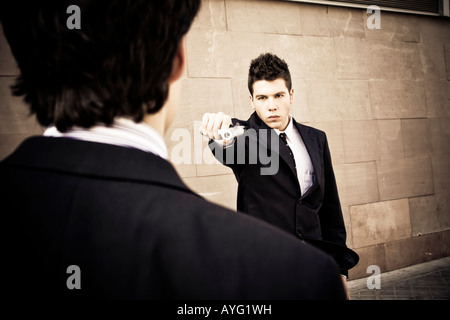 Ben vestito uomo puntando a un altro con una pistola Foto Stock