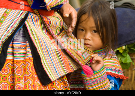 Giovane fiore ragazza Hmong nasconde nella sua madre s gonna Bac Ha mercato vicino a Sapa Vietnam Foto Stock