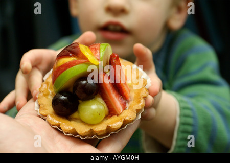 Un giovane ragazzo di raggiungere per una crostata di frutta Foto Stock