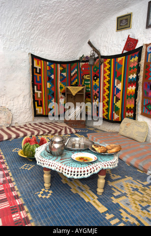 Tè per visitatore in metropolitana troglodita berbero home con colorati tappezzerie e pavimento cuscini Matmata Tunisia Foto Stock