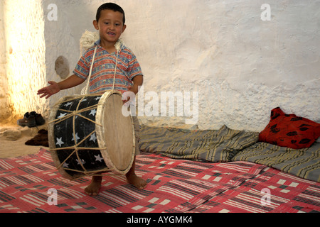 Ragazzo birichino batte il tamburo con le mani nel sotterraneo della famiglia berbera home Matmata Tunisia Foto Stock