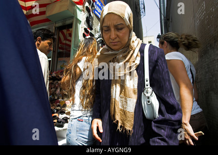 Donna in abiti tradizionali rende la sua strada trafficata stradina Medina Tunisi Tunisia Foto Stock