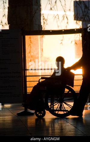 Uomo disabile essendo spinto in carrozzella Foto Stock