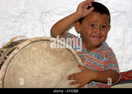 Ragazzo birichino batte il tamburo con le mani nel sotterraneo della famiglia berbera home Matmata Tunisia Foto Stock