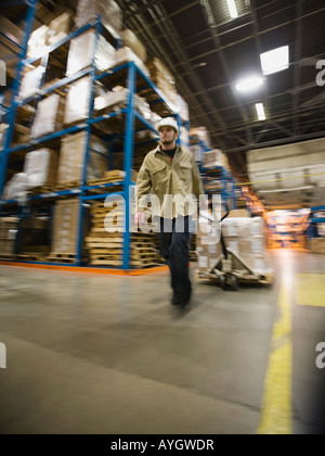 Lavoratore di magazzino palette di trazione Foto Stock