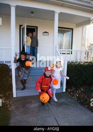 I bambini vestiti in costumi di Halloween lasciando house Foto Stock