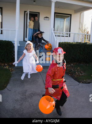 I bambini vestiti in costumi di Halloween lasciando house Foto Stock