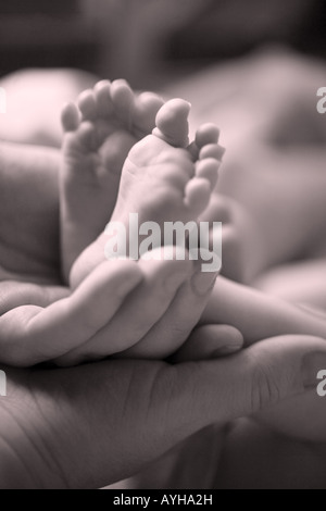 Una madre che tiene i piedi del suo bambino. Foto Stock