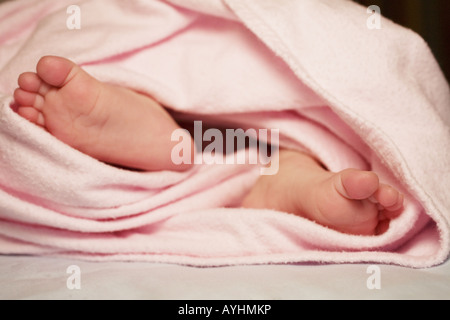 I piedi di un bambino dolce avvolti in una coperta rosa. Foto Stock