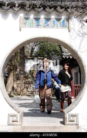 Giovani visitatori cinesi al famoso,storica collina della tigre Pagoda giardini di Suzhou Cina camminando attraverso una porta la luna Foto Stock