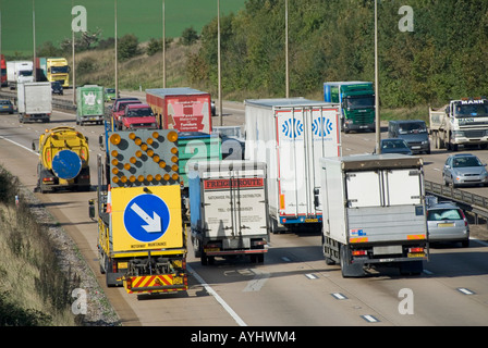 Spazzatrice stradale meccanica e veicolo di protezione con freccia segno spazzare pietre da drenaggio francese vista posteriore del traffico camion M25 autostrada Essex UK Foto Stock