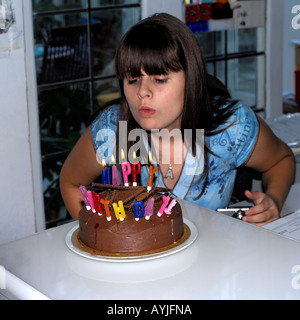 Adolescente soffiando le candeline sulla torta di compleanno Inghilterra Foto Stock