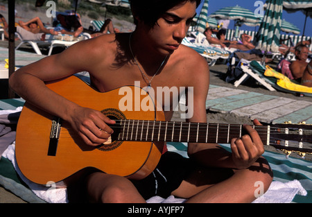 Giovane uomo a suonare la chitarra in una spiaggia del Languedoc Roussillon Foto Stock