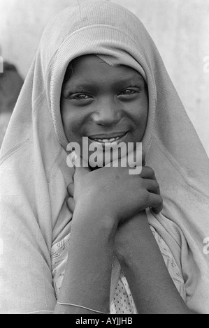 Ritratto in bianco e nero di una ragazza musulmana sorridente che ricopre la testa con il suo maglione. Harar, Etiopia, Africa Foto Stock