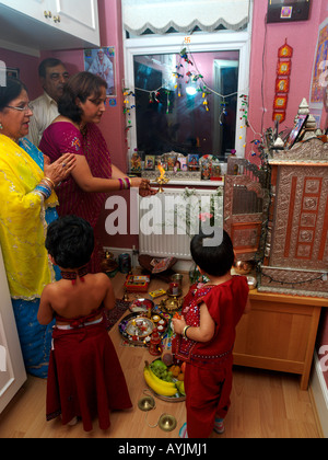 Famiglia in adorazione nel Santuario Madre Holding lampada accesa a Diwali Festeggiamenti in casa Tooting London Inghilterra England Foto Stock