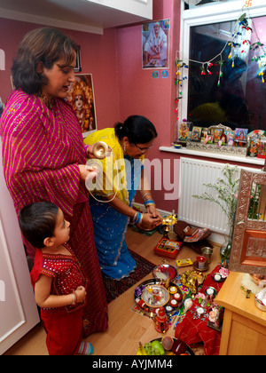 Famiglia adoriamo la nonna con la lampada accesa e la madre con i simboli in corrispondenza di Diwali Festeggiamenti in casa Tooting London Inghilterra England Foto Stock