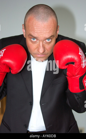 Balding l uomo nella sua 40s che indossa un abito nero è il sollevamento red guantoni da pugilato Foto Stock