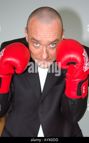 Balding l uomo nella sua 40s che indossa un abito nero è il sollevamento red guantoni da pugilato Foto Stock