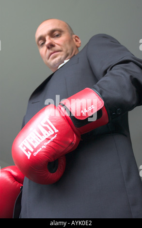 Bald business man indossa guantoni da pugilato guarda verso il basso nella fotocamera Foto Stock