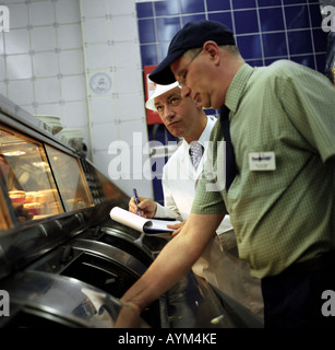 Un ispettore di cibo in un chip shop Foto Stock