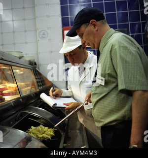 Un ispettore di cibo in un chip shop Foto Stock