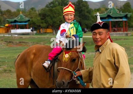 Pullman con una bambina di 4 anni a cavallo che partecipa alle corse ippiche del festival Naadam, Ulan Bator, Mongolia Foto Stock