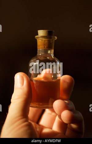 L'uomo detiene piccola bottiglia di vetro di liquido in mano Foto Stock