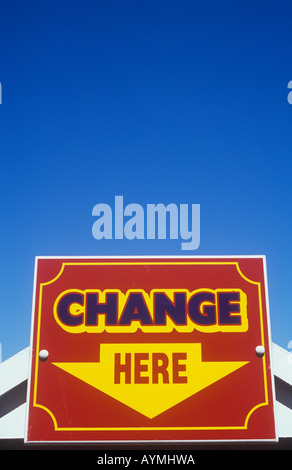 Close up di rosso giallo e il cartello blu con la freccia rivolta verso il basso contro il cielo blu e chiaro indicando modifica qui Foto Stock