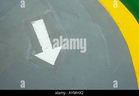 Chunky la freccia bianca rivolta verso il visualizzatore sul manto di asfalto verniciato in colore grigio chiaro con curvatura giallo e bordo verde Foto Stock