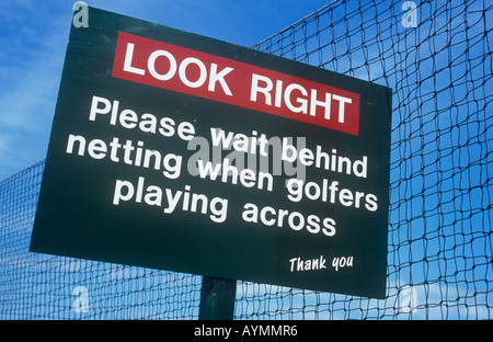 Segno sul sentiero pubblico accanto a rete di sicurezza precisando guardare a destra si prega di attendere alle spalle di netting quando i golfisti giocando attraverso la ringrazio Foto Stock