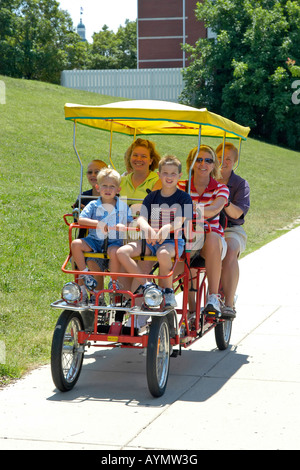 Il giorno della famiglia fuori a godersi il sole estivo utilizzando Peddle bike. Foto Stock