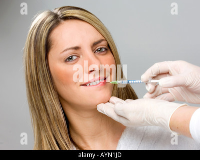 La donna la ricezione di botox iniezione nel labbro guardando ansioso Foto Stock