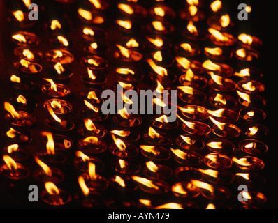 Righe di bruciare candele votive, lampade ad olio. Foto Stock
