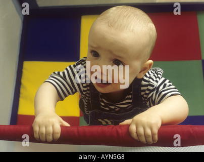 Il pianto baby boy in piedi in un lettino da viaggio Foto Stock