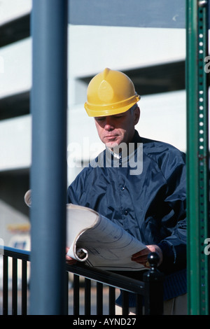 Costruzione caucasica foreman guardando blueprint su un cantiere indossano hardhat Foto Stock
