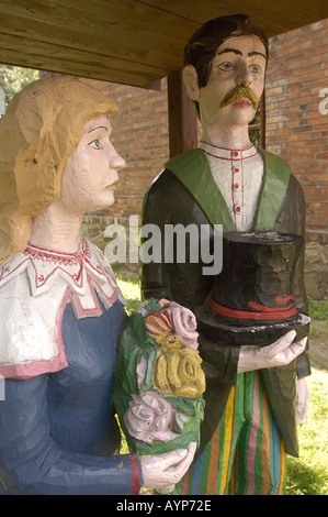 Statue folcloristiche in legno presso il Mazowsze Open Air Museum di Sierpc, Polonia. Sculture in legno tradizionali polacche di un uomo e di una donna in costumi popolari. Foto Stock