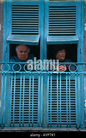 Italia Campania Napoli San Giorgio a Cremano coppia di anziani guardando fuori dal turchese aprire persiane in legno sopra street Foto Stock