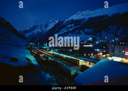 La Svizzera Ski resort chalets e la stazione ferroviaria di coperta di neve montagna paesaggio della valle di notte con luci da windows Foto Stock