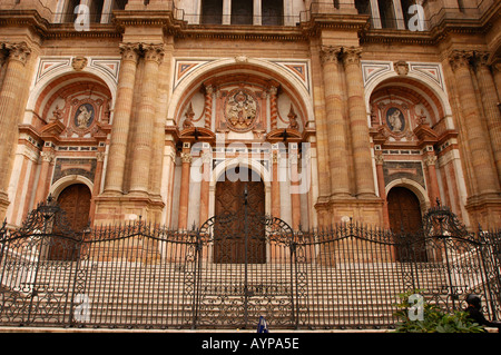 La grande facciata della Cattedrale di Malaga a Malaga, Andalusia, Spagna, presenta sculture in pietra ornate, ingressi ad arco e una recinzione in ferro battuto. Foto Stock