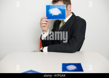 Imprenditore tenendo una foto con la telecamera e nuvole Foto Stock