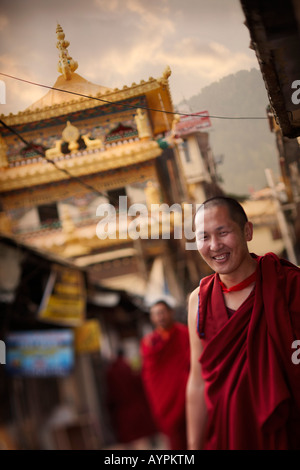 Un ritratto di un sorridente monaco tibetano in un villaggio street al tramonto. Foto Stock