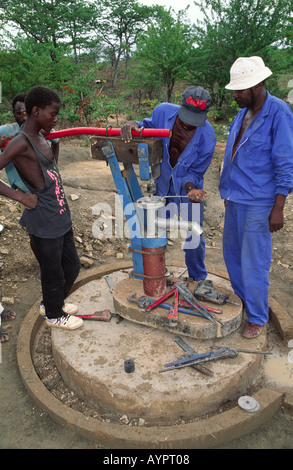 Tecnici dell'acqua che montano una testa della pompa alla nuova pompa dell'acqua della comunità. Zimbabwe Foto Stock