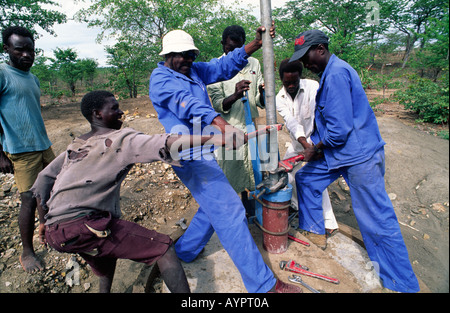 Tecnici dell'acqua che montano una testa ad una nuova pompa dell'acqua del villaggio nr. Binga nello Zimbabwe rurale Foto Stock