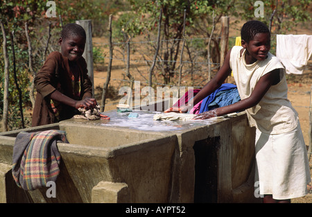 Due ragazze lavaggio vestiti presso il villaggio locale pompa acqua e lavatoio. Zaka, Zimbabwe Foto Stock