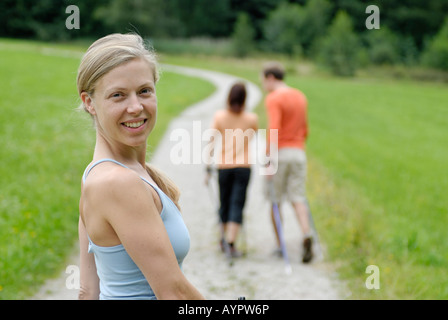 Giovane donna Nordic walking (sci a piedi) dietro un paio Foto Stock