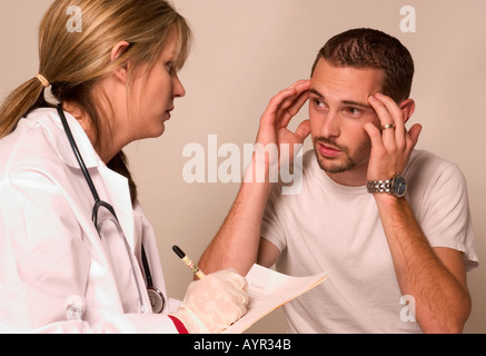 Una donna caucasica di medicina generale parla con un paziente di sesso maschile che soffre di mal di testa durante la consultazione, USA. Foto Stock