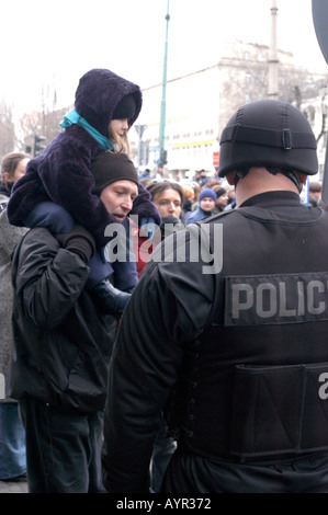 Dimostrazione contro la guerra a Poznan, Polonia. Un uomo porta un bambino sulle spalle di fronte a un agente di polizia con equipaggiamento tattico durante una protesta pubblica. Foto Stock